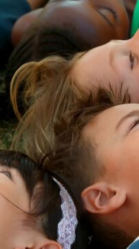 Vertical video: Pulling back camera revealing children lying on grass, watching sky, lace headband