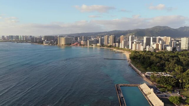 Flying towards Waikiki Beach, park and tall buildings by the ocean coast, Honolulu city panorama
