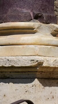 ancient roman column base layered pale marble moldings dark porphyry shaft chips cracks appear tempio del divo romolo reveals up close view rome italy empire emperor 