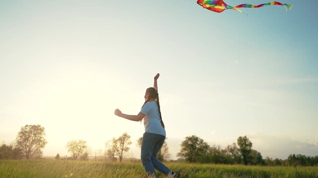 Person flying in field. Silhouette of young girl holding kite while running. Girl is running with a kite and a kite. An individual manipulating a kite in a meadow lifestyle.