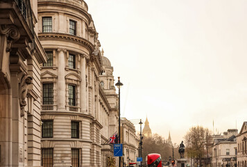 Obraz premium London cityscape featuring historic architecture, iconic red bus, and the distant Big Ben clock tower under a bright sky