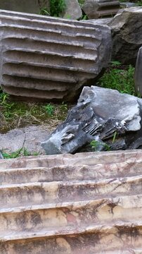 broken fluted marble columns carved stone blocks lie scattered among grass weeds chipped edges grooves weather stained surfaces highlight ancient roman craftsmanship domus rome italy empire 