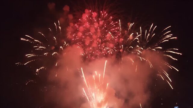Sweeping crane shot of Chinese New Year firecracker display bright red explosions golden sparks smoke night sky celebration