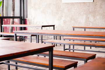 A calm cafe setting features empty wooden tables and chairs in a food hall. Soft lighting creates an inviting atmosphere, offering a perfect spot for relaxation.