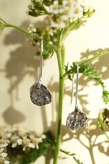 Elegant Silver Earrings with Floral Design Displayed Against a Soft Floral Backdrop, Jewelry Concept
