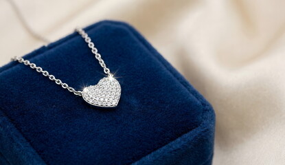 Generated AI close-up of a luxury silver heart-shaped pendant necklace pav&eacute;-set with sparkling diamonds, resting on a premium royal blue velvet jewelry box with soft silk background, elegant jewelry p