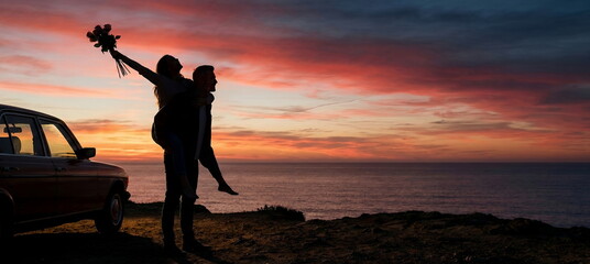 Generated AI: Breathtaking Sunset Romance; Silhouetted Couple Celebrate Love with Roses and a Vintage Car on a Dramatic Coastal Cliff.