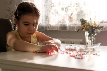 Creative World of Little Girl. She is Crafting Colorful Jewelry at Home on a Sunny Afternoon.