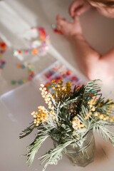 Little Girl is Crafting at Home Jewelry with Colorful Beads and Delicate Mimosa Flowers Decor.