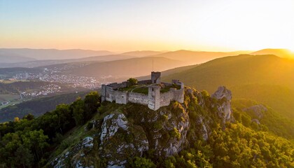 Ancient stone castle ruins atop a mountain illuminated by a brilliant sunset