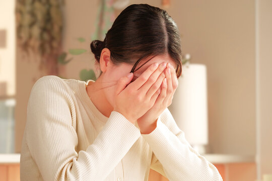 ショックを受けて顔を覆う若い女性