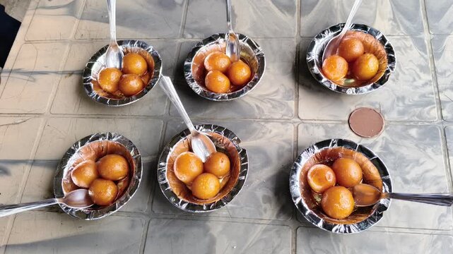 Traditional Indian sweet Gulab Jamun served in disposable bowls on a table