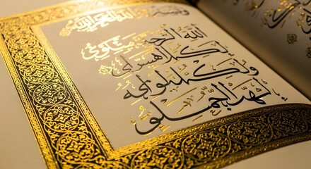 Fototapeta premium A book with arabic calligraphy and gold border on a table with a white surface and light shining on it from the side