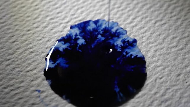 Blue Ink Drop Crystallizing and Spreading on Textured White Paper