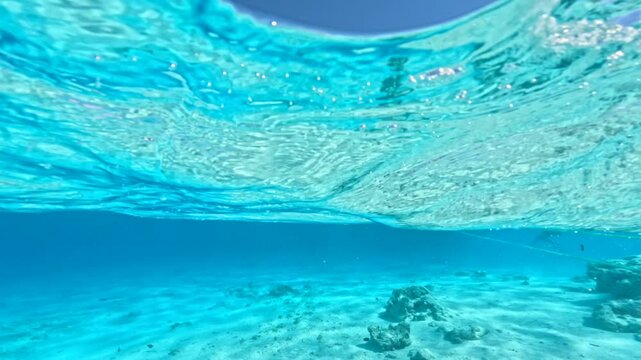Half underwater view of tourist yachts anchored in turquoise lagoon during snorkeling excursion in Ras Mohammed National Park