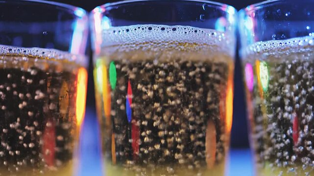 Close-up of three glasses of beer with bubbles and colorful reflections, party atmosphere