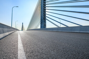 Empty asphalt road and modern cable stayed bridge under blue sky