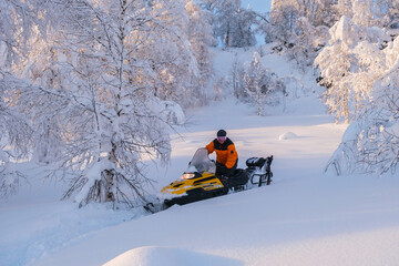 Woman on a snowmobile moving in the winter forest in the mountains of the Southern Urals