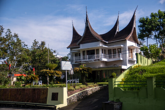 Bukittinggi, Indonesia - April 09, 2024 : The Minang International Hotel displays elegant traditional Minangkabau roof architecture under a clear blue sky surrounded by lush greenery.