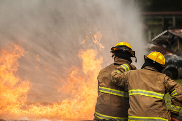 Naklejka premium Firefighters extinguishing burning car during emergency response