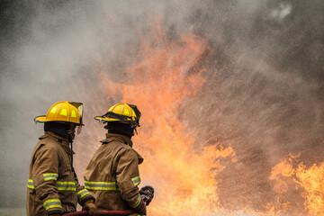 Naklejka premium Firefighters extinguishing burning car during emergency response