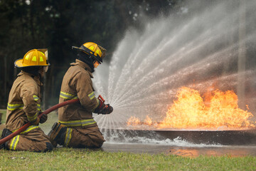 Naklejka premium Firefighters extinguishing burning car during emergency response