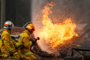 Firefighters extinguishing burning car during emergency response
