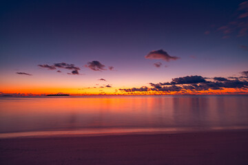 Fototapeta premium Peaceful majestic tropical ocean beach with sunrise and sunset sky, white fluffy clouds on horizon, inspirational meditation nature background, serene tropical landscape, relaxing scene