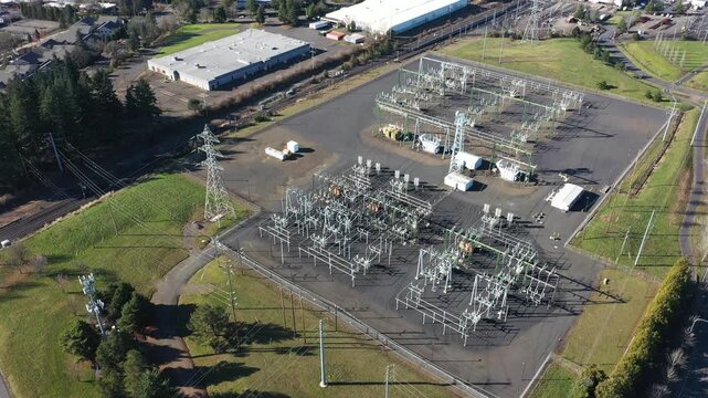 4K aerial drone footage of large electric power substation and high voltage power lines in Beaverton, Oregon, showing transmission towers, transformers, and distribution infrastructure from above	