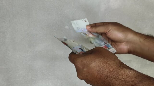 Blind person hand touch money surface for identifying size or counting kuwaiti dinar (kwd) kuwait currency notes before paying. Raised dots and tactile cues on banknote concept. Closeup view.