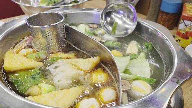 Close-Up of hand stir hot spicy malatang on soup pot