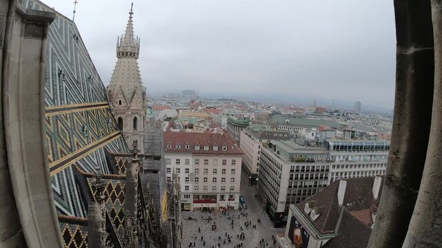 A captivating aerial view of a historic city featuring intricate architecture and a tall tower, shrouded in clouds. The bustling streets below are filled with colorful buildings, creating a vibrant ur