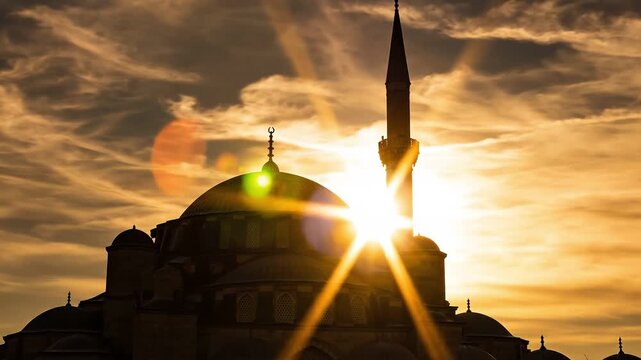 Silhouette of a traditional dome mosque during sunrise with bright sun rays and orange sky in a scenic architectural landscape view