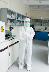 Clinical lab is showing full white protective suit centered, microscope and biohazard cabinet