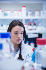 Reagent bottles with red and blue caps are sitting on cluttered lab bench with shelving blurred