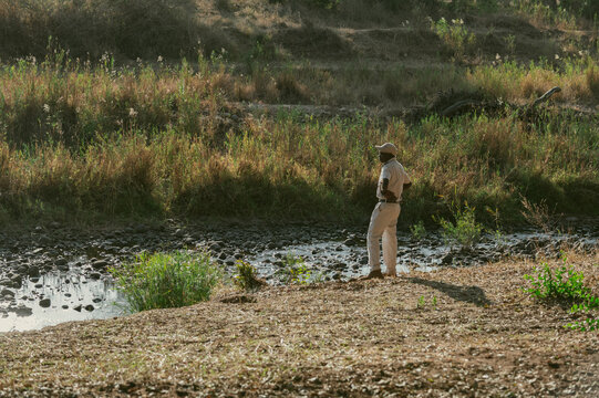 Person stands by the riverbank looking pensive in afternoon light