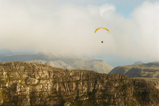 Single paraglider soaring over mountains near Cape Town