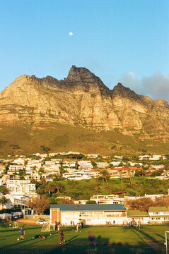 Soccer players enjoy a game on the field with mountains and moon rise