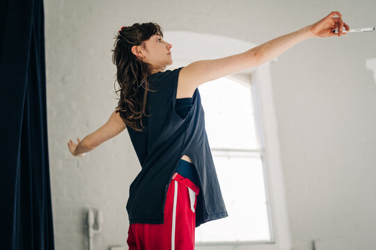 Woman dancing with outstretched arms holding marker