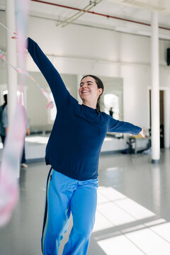 Smiling woman dancing with colorful ribbon in studio