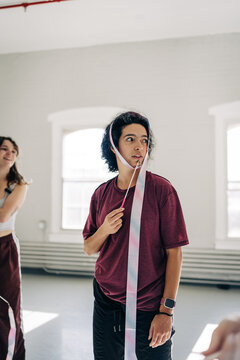Young person holding rhythmic gymnastics ribbon in studio