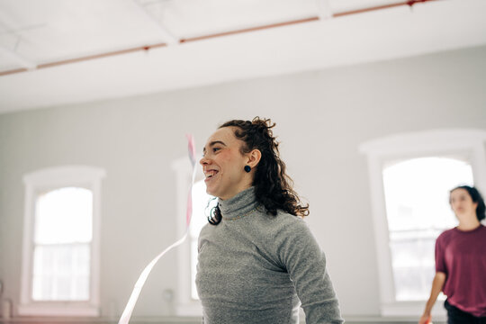 Woman joyfully exercising with rhythm ribbon indoors