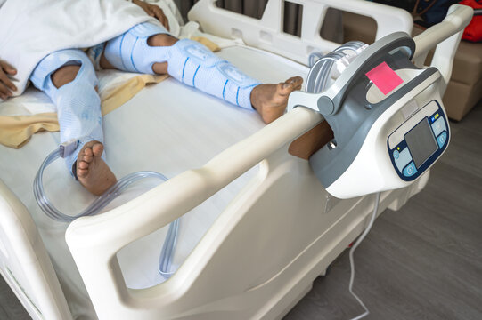 Close up unknown patient lying on hospital bed with Sequential Compression Device (SCD) on both legs after surgery