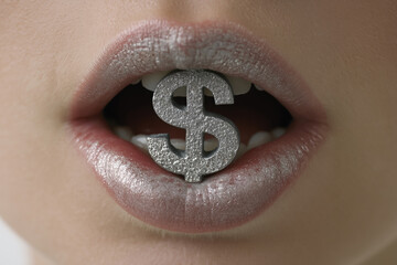 Female lips and teeth biting silver $ USA dollar money symbol