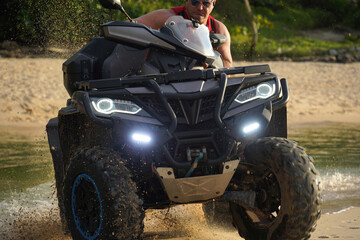 Fototapeta premium A man engages in extreme ATV riding on sand beach early in the morning