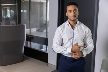 Fototapeta premium Asian male in business attire standing next to glass partition in office corridor, copy space