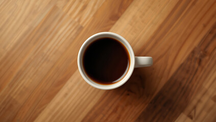 Obraz premium Fresh black coffee in white mug on warm wooden table, cozy morning mood