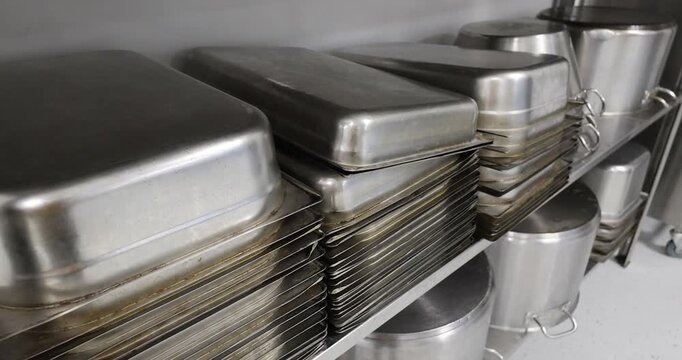 Details with stainless steel kitchen pots, pans and utensils in a professional canteen or hospital kitchen.