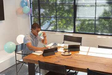 French press brewing coffee beside two tablets and notebook resting, pastel balloons
