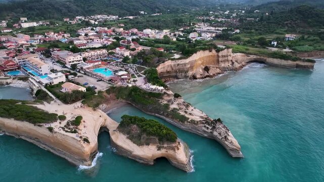 Sweeping high-altitude aerial drone orbit of Sidari, Corfu, Greece, showcasing the famous Canal d'Amour cliffs and the entire coastal town